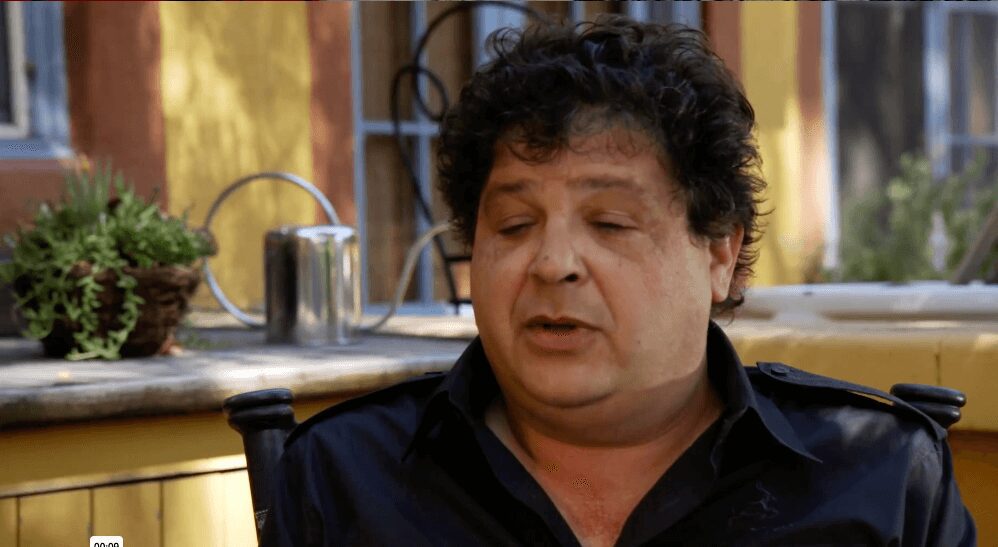 Man sitting outdoors with eyes closed.